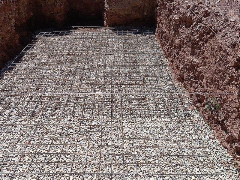 Excavación con base de grava y mallazo de acero atado, preparado para hormigonar la losa de cimentación