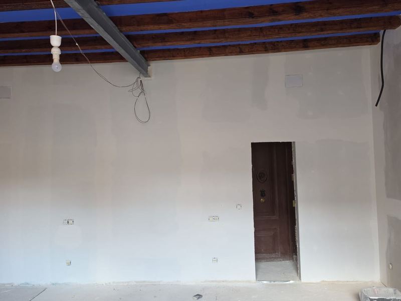 Pared alisada con los cajetines de la instalación eléctrica, vigas de madera y viga metálica a la vista